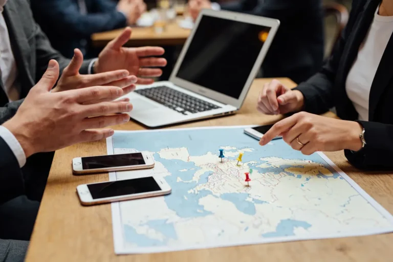 Personnes discutant autour d'une carte sur une table avec téléphones et ordinateur portable.