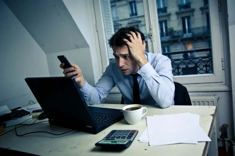 Homme stressé, chemise, cravate, regardant téléphone et ordinateur portable, café, calculette, documents, bureau, fenêtre ouverte.